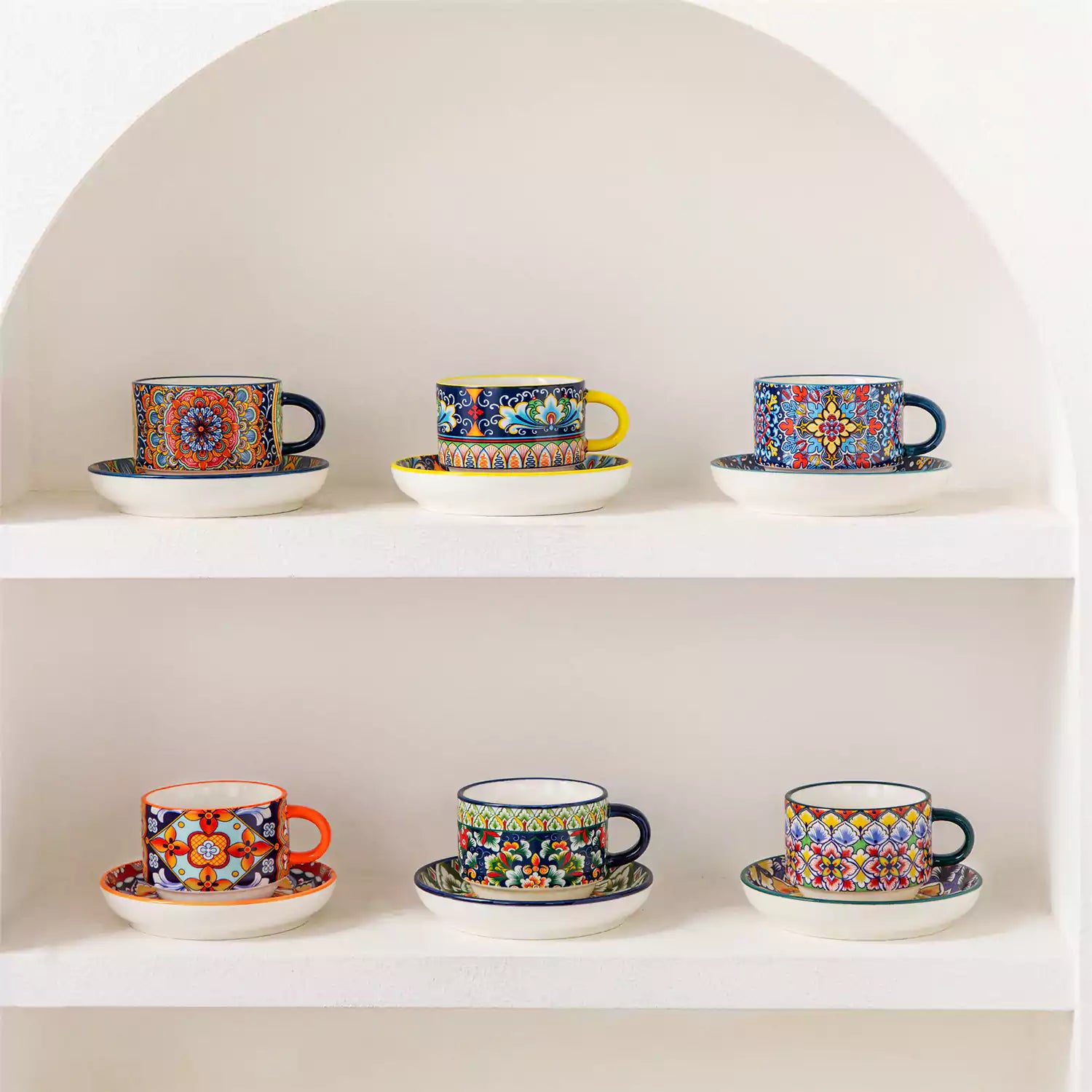 Simi 12 piece porcelain cafe set with 5oz flat white cups and saucers in vibrant boho chic floral patterns on a black metal storage rack with a magazine and napkin on a wooden table
