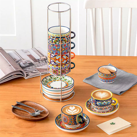 Simi 12 piece porcelain cafe set with 9oz flat white cups and saucers in vibrant boho chic floral patterns on a black metal storage rack with a magazine and napkin on a wooden table