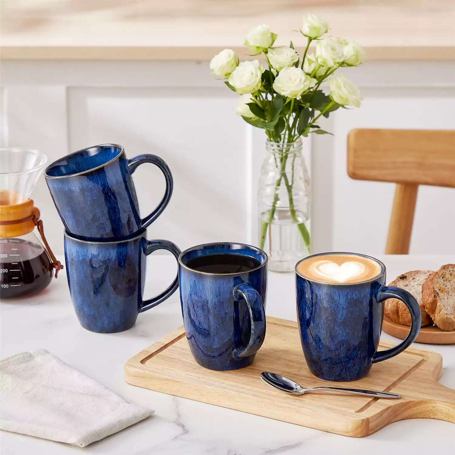 Set of 4 Starry 16oz stoneware mugs in blue with reactive glaze finish styled on a marble countertop with fresh coffee