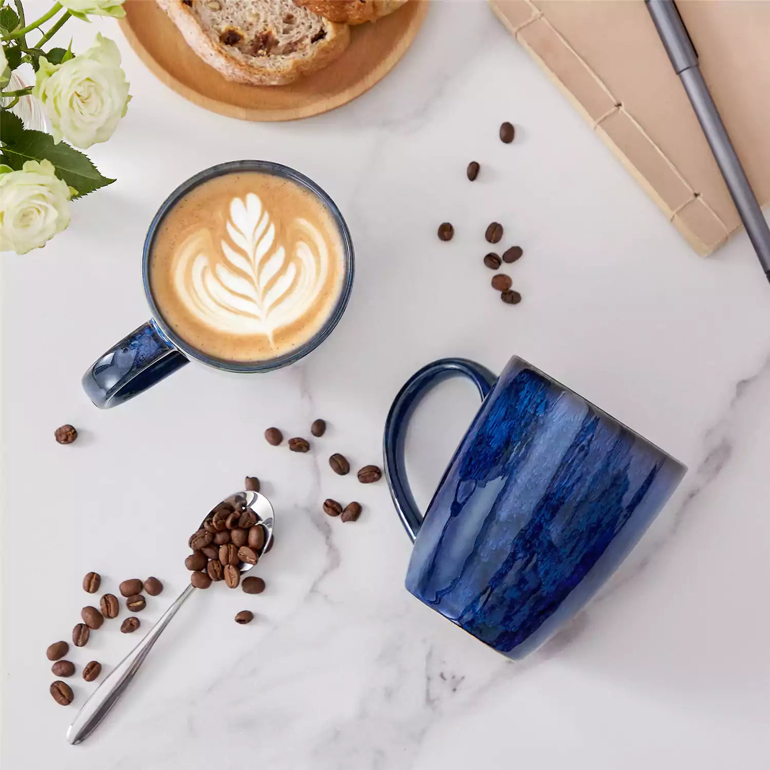 Set of 4 Starry 16oz stoneware mugs in blue with reactive glaze finish styled on a marble countertop with fresh coffee