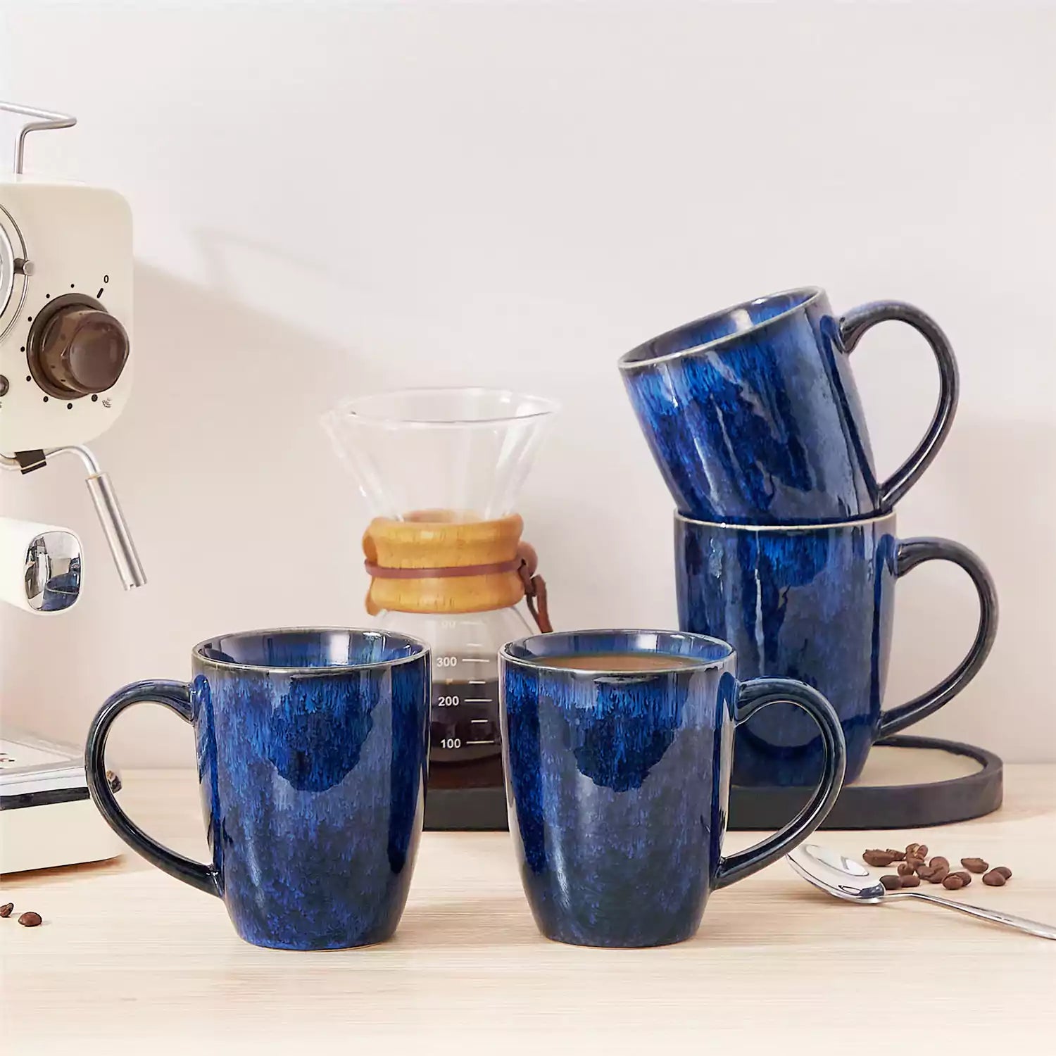 Set of 4 Starry 16oz stoneware mugs in blue with reactive glaze finish styled on a marble countertop with fresh coffee