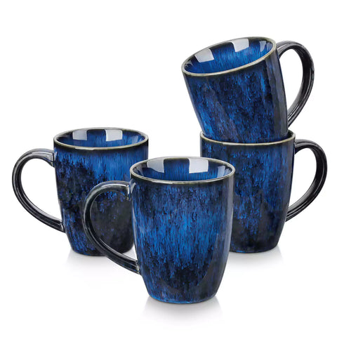Set of 4 Starry 16oz stoneware mugs in blue with reactive glaze finish styled on a marble countertop with fresh coffee