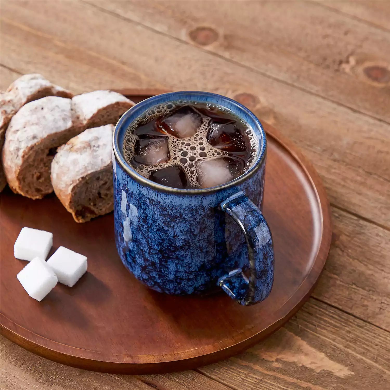 Four starry blue 16oz stoneware mugs with latte art on wooden table beside coffee brewing equipment
