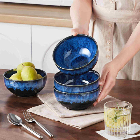 Starry reactive glaze cereal bowls in blue on a rustic wooden table - filled with creamy soup - pasta - and fresh fruit salad for a cozy - celestial dining vibe