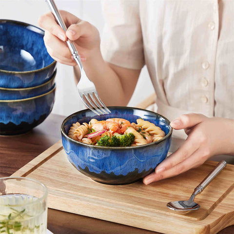 Starry reactive glaze cereal bowls in blue on a rustic wooden table - filled with creamy soup - pasta - and fresh fruit salad for a cozy - celestial dining vibe