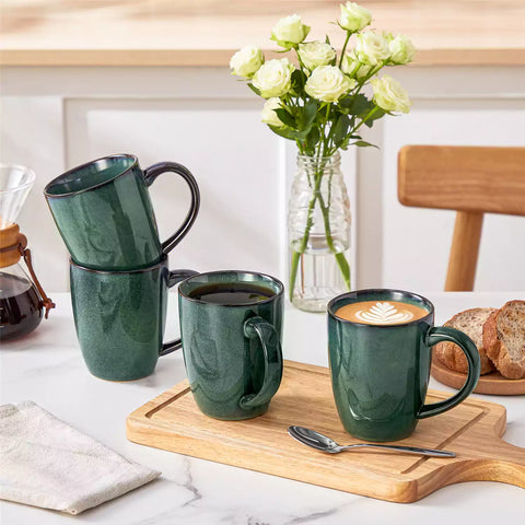 Set of 4 Starry 16oz stoneware mugs in green with reactive glaze finish styled on a marble countertop with fresh coffee