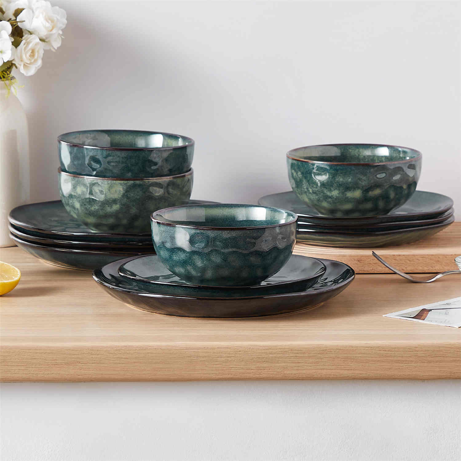 Starry 12-piece stoneware dinnerware set in green on a light wooden table - styled with lamb chops - pastries - coffee pot - and lemon water for a cozy farmhouse breakfast scene