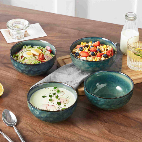 Starry reactive glaze cereal bowls in teal green on a rustic wooden table - filled with creamy soup - pasta - and fresh fruit salad for a cozy - celestial dining vibe
