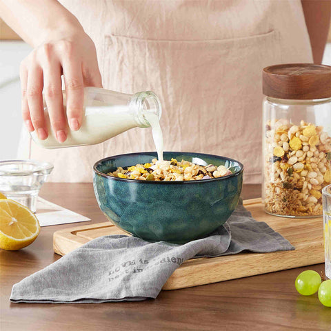Starry reactive glaze cereal bowls in teal green on a rustic wooden table - filled with creamy soup - pasta - and fresh fruit salad for a cozy - celestial dining vibe