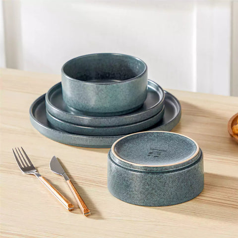 Blue reactive glaze stoneware dinner plates styled with food on rustic wood table with woven placemats modern minimalist tableware set