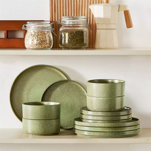 Green reactive glaze stoneware dinner plates styled with food on rustic wood table with woven placemats modern minimalist tableware set