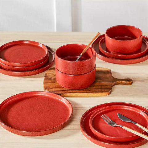 Red reactive glaze stoneware dinner plates styled with food on rustic wood table with woven placemats modern minimalist tableware set