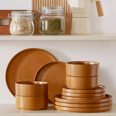 Caramel reactive glaze stoneware dinner plates styled with food on rustic wood table with woven placemats modern minimalist tableware set