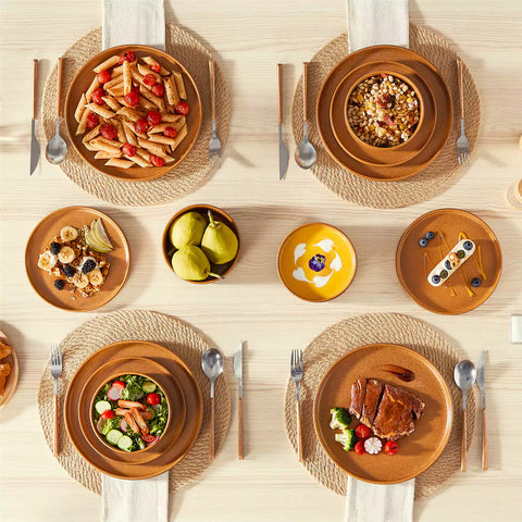 Caramel reactive glaze stoneware dinner plates styled with food on rustic wood table with woven placemats modern minimalist tableware set