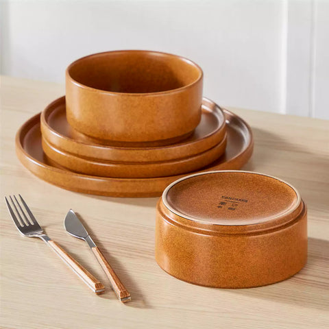 Caramel reactive glaze stoneware dinner plates styled with food on rustic wood table with woven placemats modern minimalist tableware set