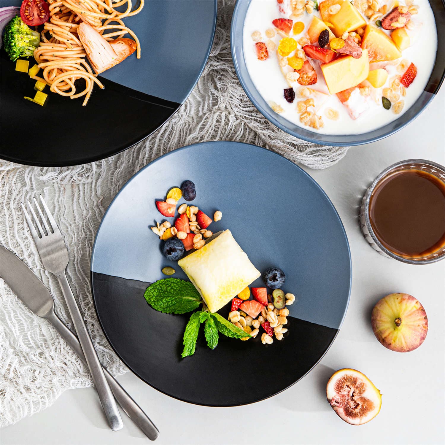 Accel 16-piece blue and black two-tone semi-matte dinnerware set with plates and bowls serving pasta and fruit