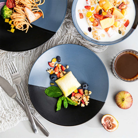 Accel 16-piece blue and black two-tone semi-matte dinnerware set with plates and bowls serving pasta and fruit